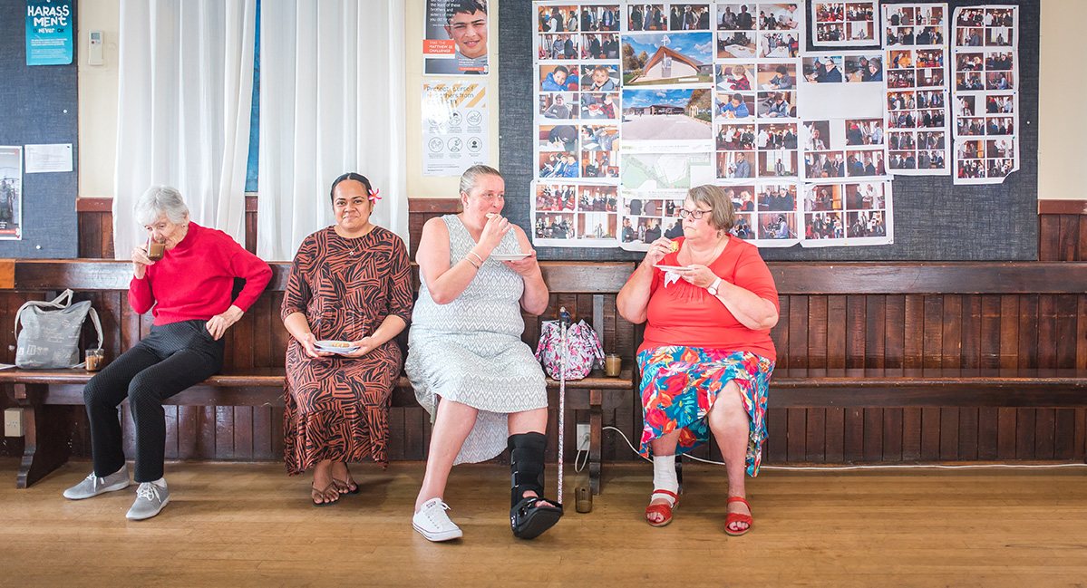 four women sitting in a line, having morning tea together